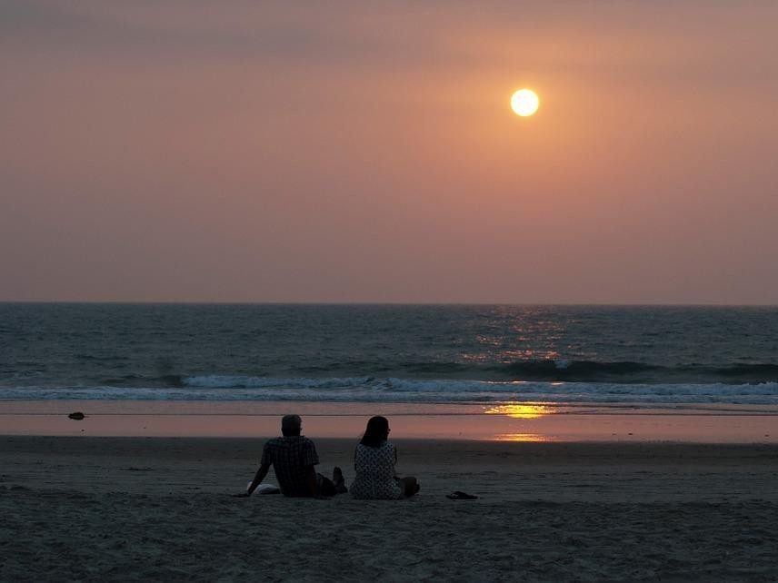 ビーチで夕焼けを眺める夫婦