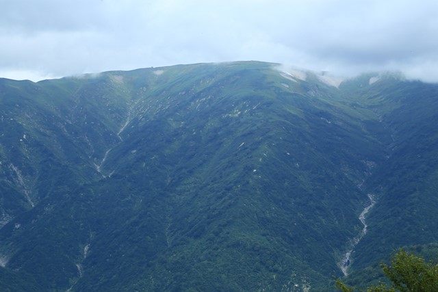 御西岳周辺の稜線上に御西岳避難小屋が見えています。
山肌を縫う谷には、幾つもの滝がかかっています。