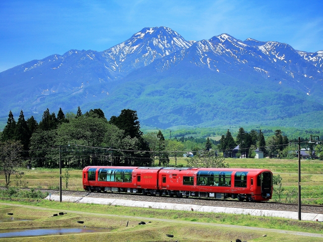 残雪の妙高の山々を背景に走る「えちごトキめき鉄道」